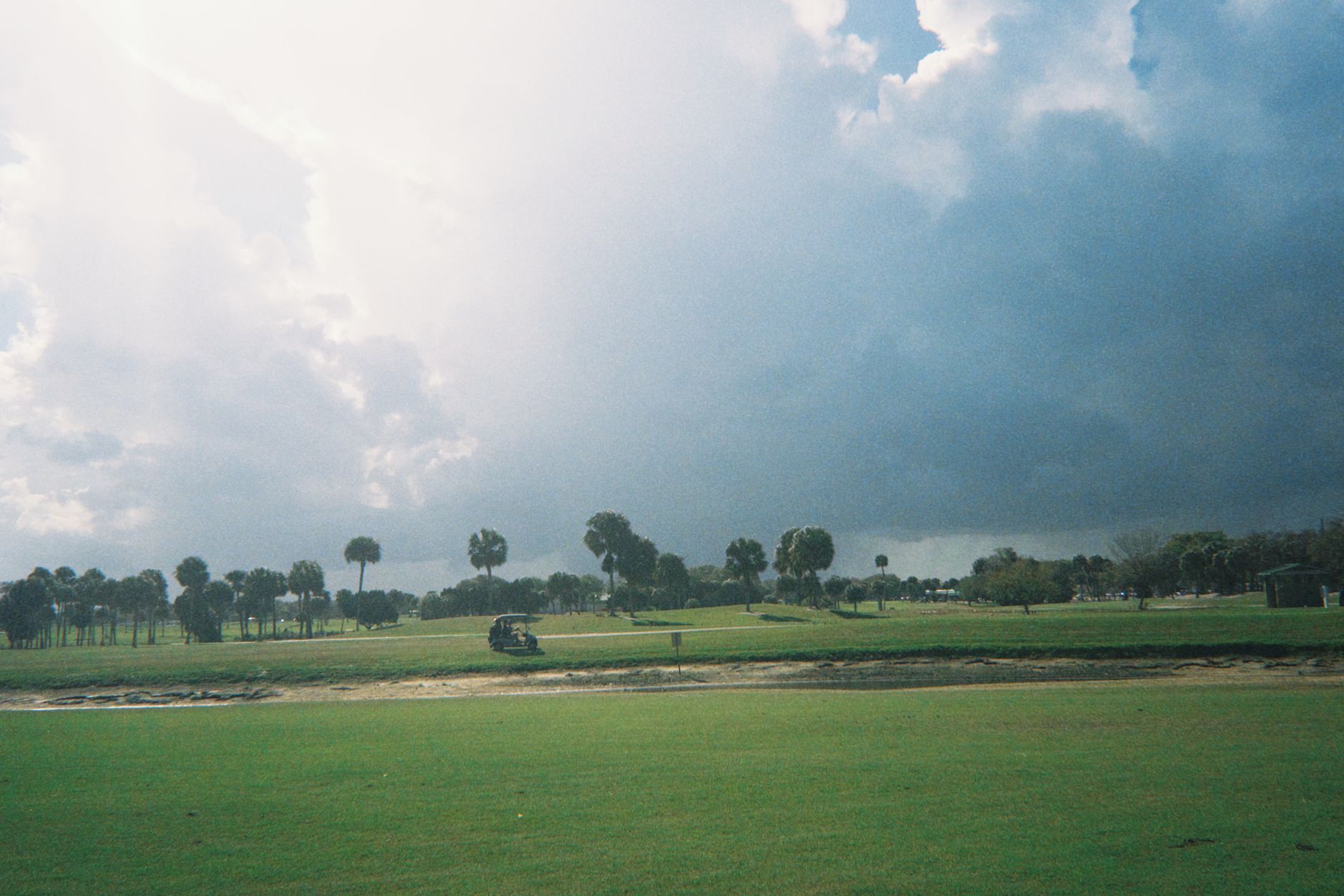 A scenic view of a golf course under a dramatic cloudy sky, capturing the essence of a day outdoors.