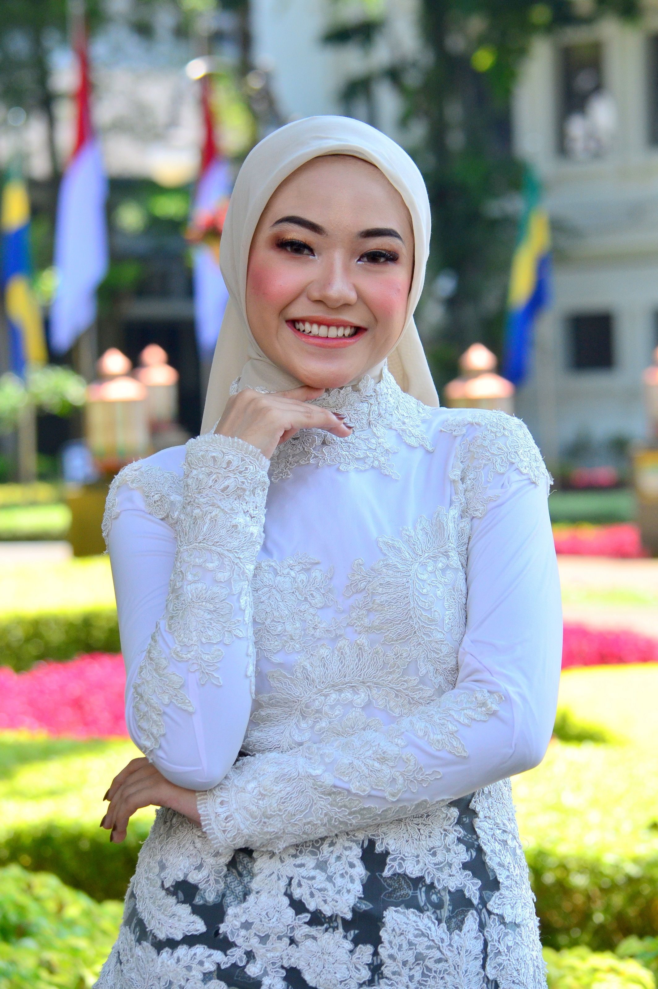 Charming woman in hijab smiling elegantly in an outdoor garden in Bandung.
