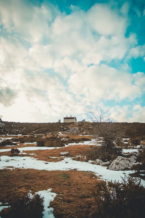 Gratis Rumah Putih Dan Coklat Di Atas Tanah Yang Tertutup Salju Di Bawah Awan Putih Dan Langit Biru Foto Stok