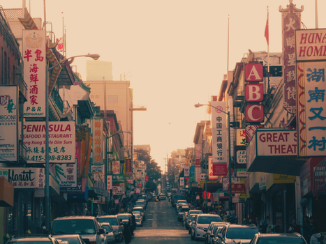 Vibrant street scene in Chinatown, San Francisco at sunset, full of colorful signs and bustling activity.
