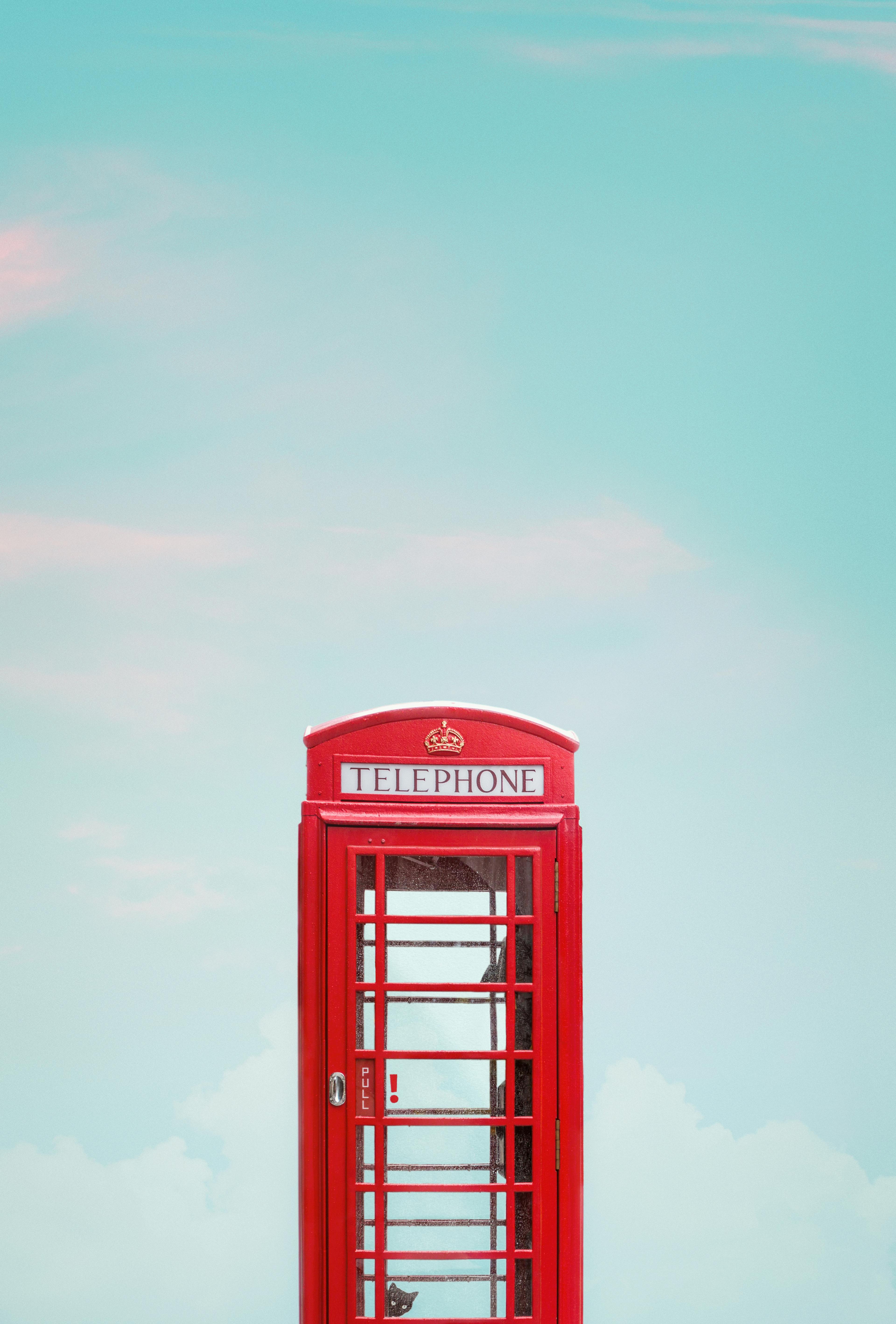 photo of red telephone booth under blue sky