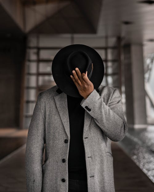 Person in Gray Coat Holding Black Hat