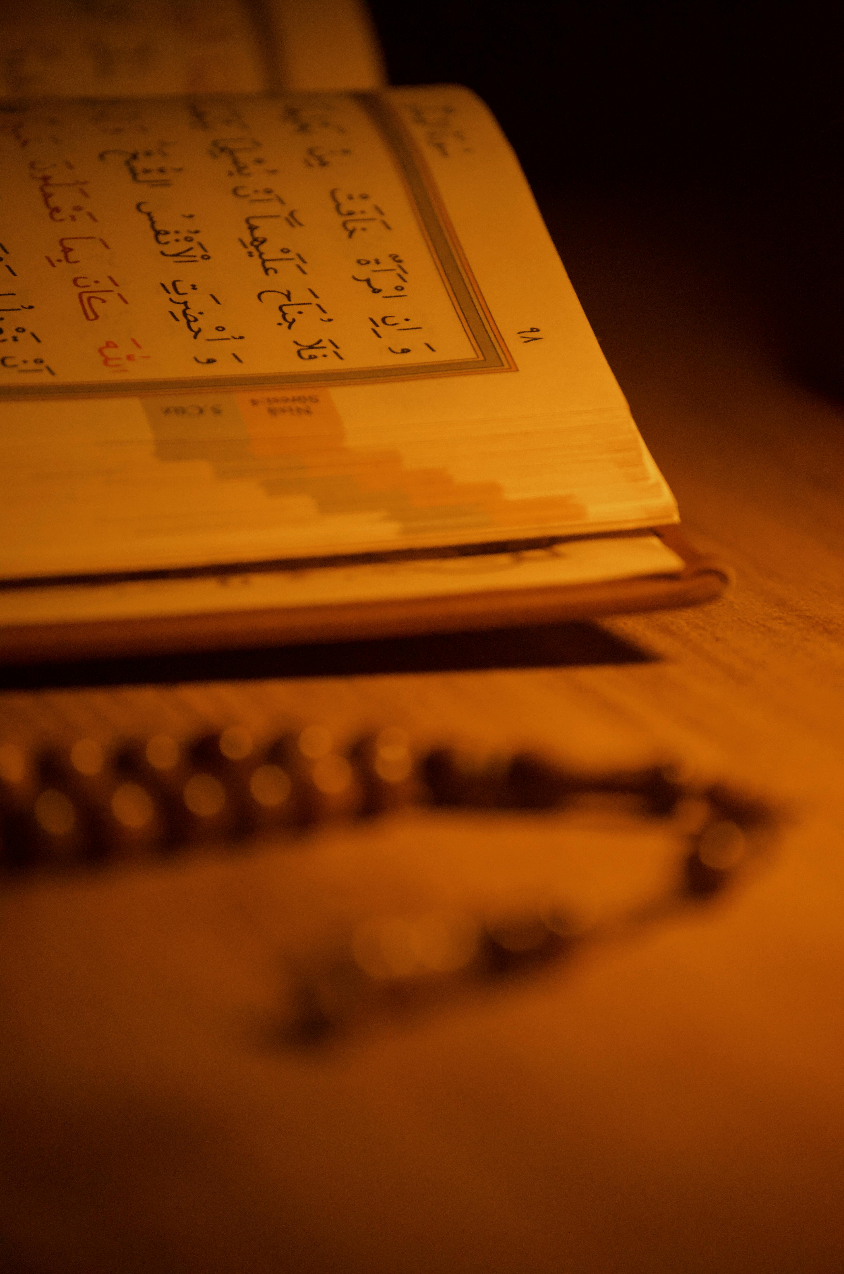 無料 テーブルの上には開かれたコーランと数珠が置かれ、暖かい光を放っています。 写真素材