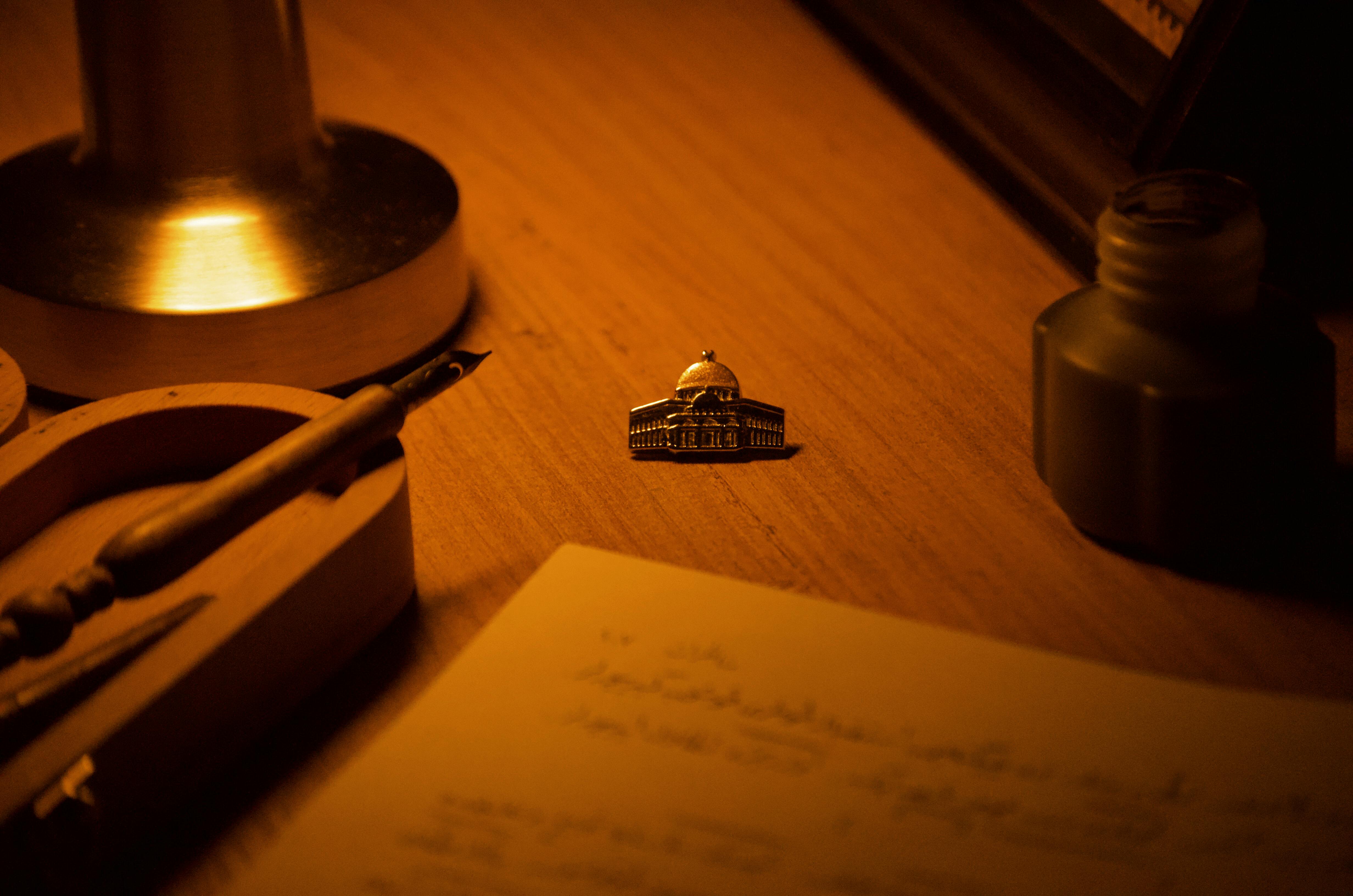 Kostenlos Schreibtischszene in warmen Farbtönen mit Lampe, Tintenfass und Dekorationsobjekt. Stock-Foto