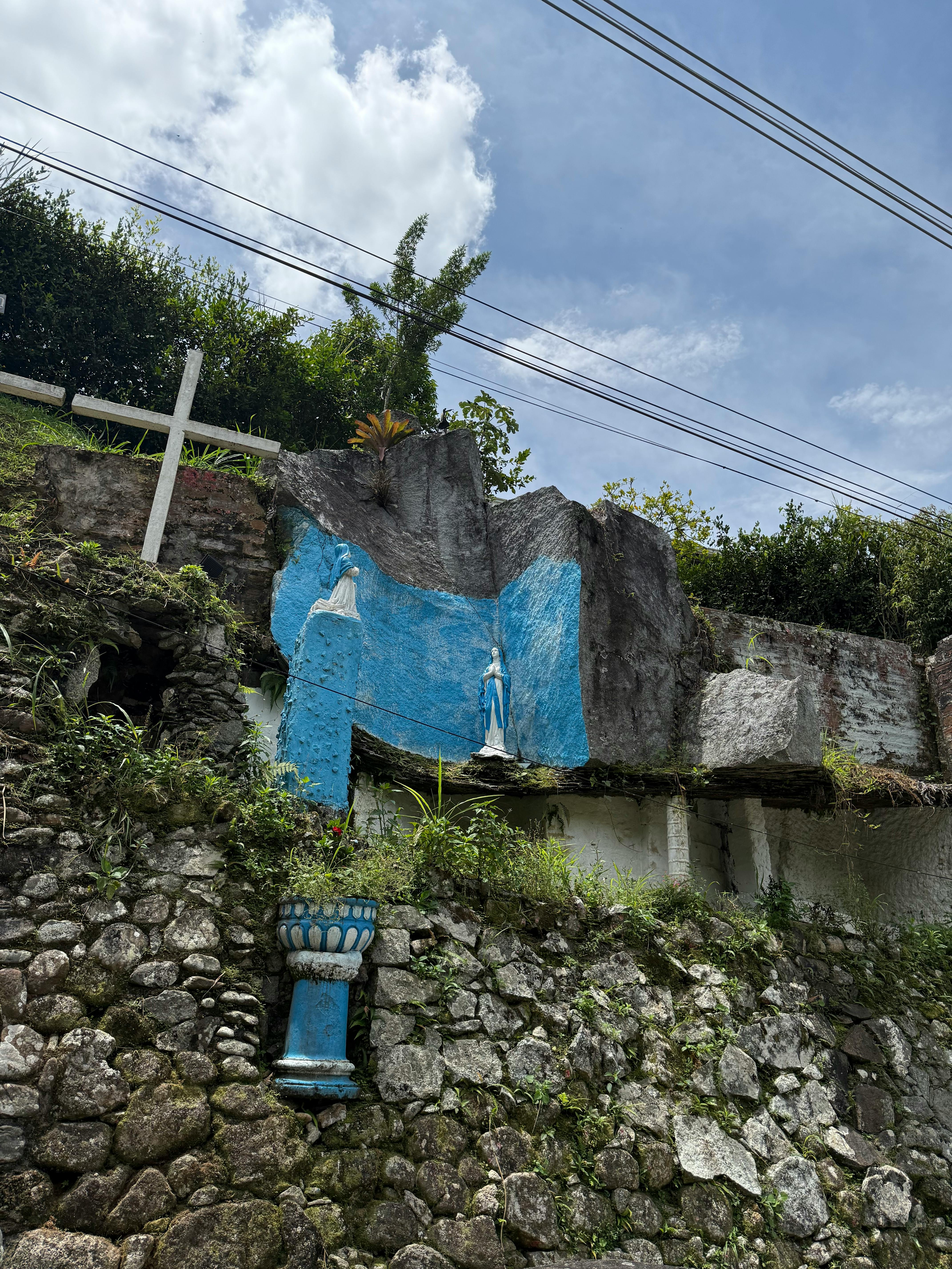 Gratuit Statuie de piatră pe un perete albastru pe o suprafață de stâncă cu verdeață. Fotografie de stoc