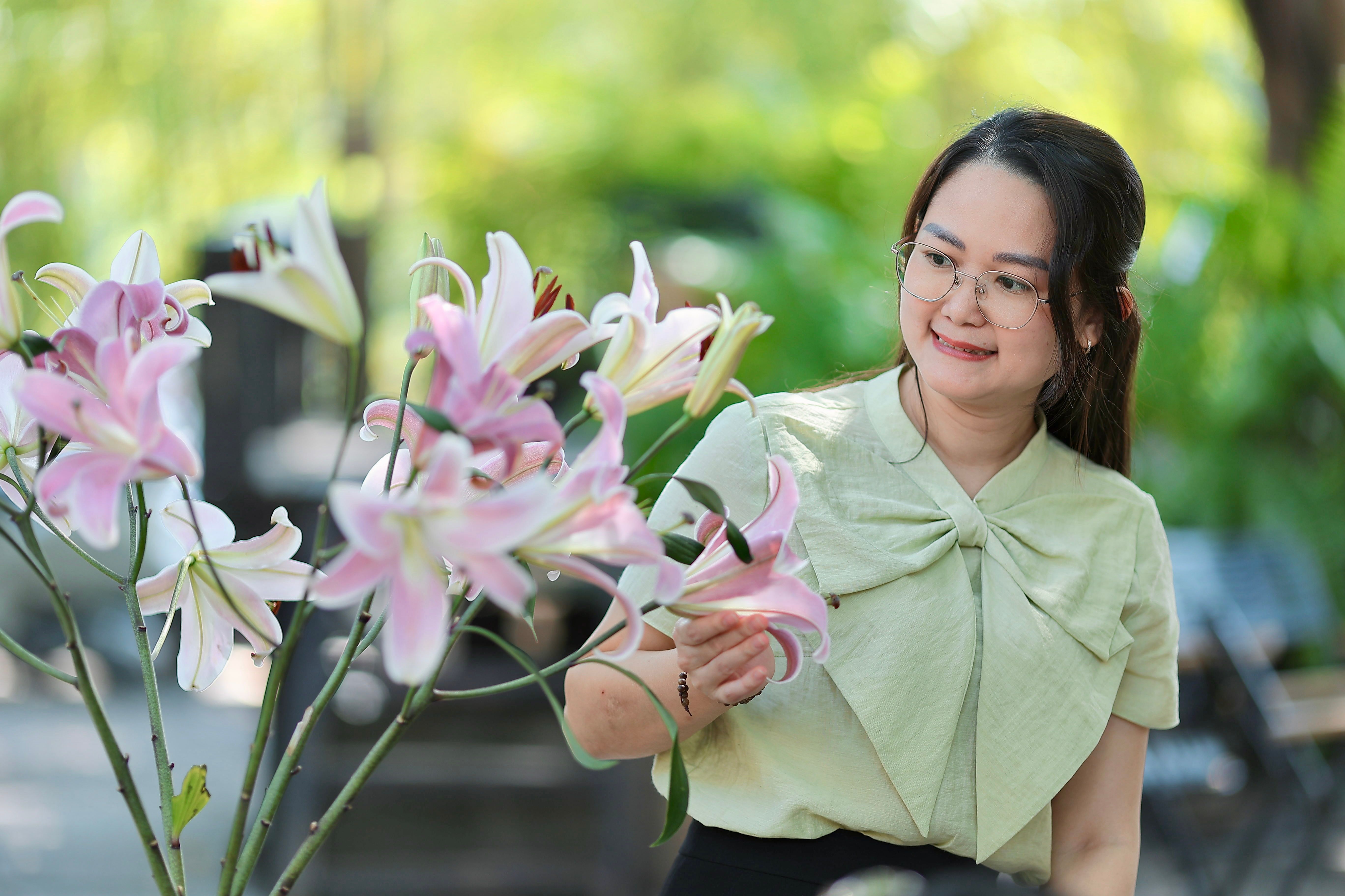 Woman Enjoying Pink Lilies in Outdoor Garden