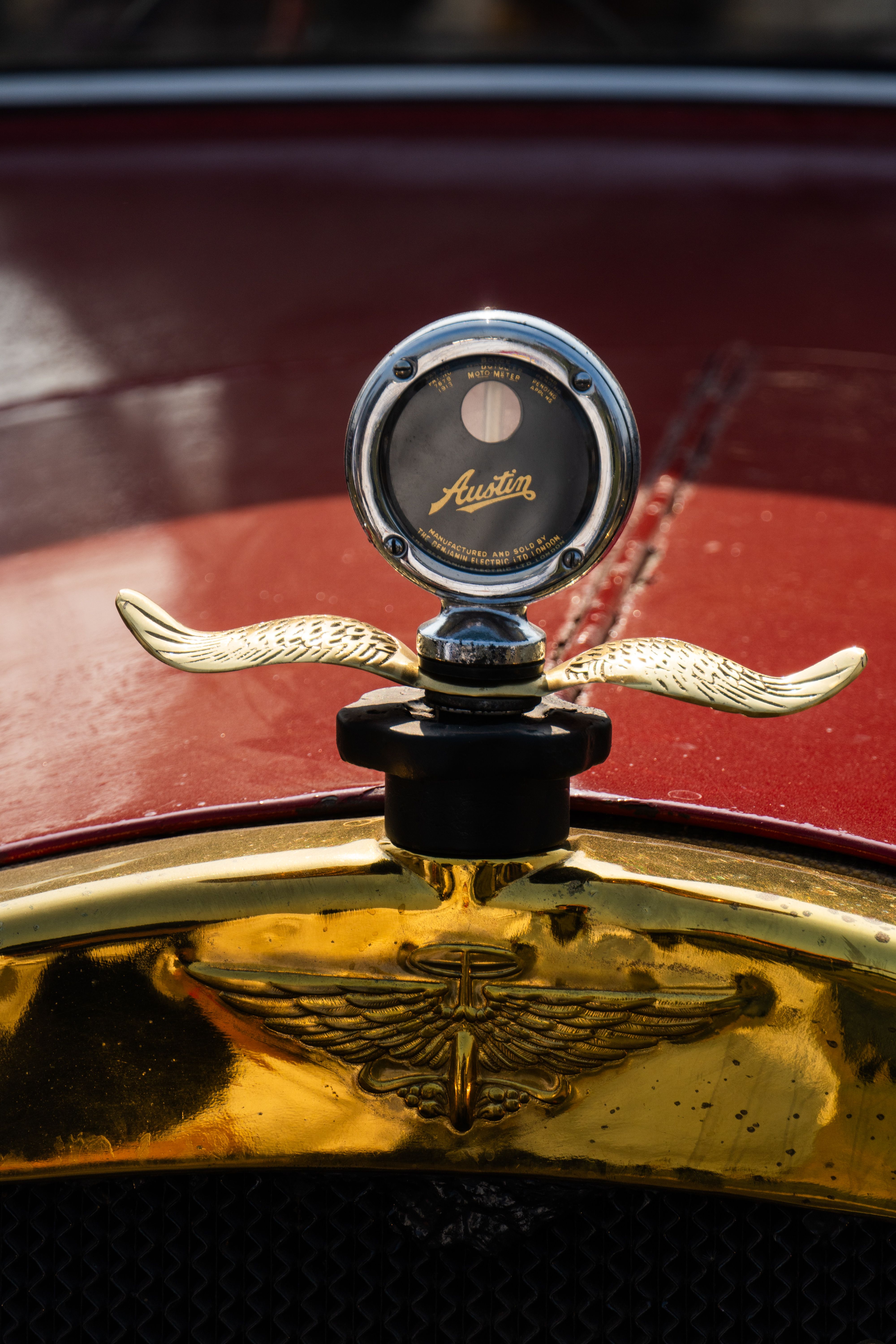 Close-up of a vintage Austin radiator cap with ornate emblem, showcasing classic car design.