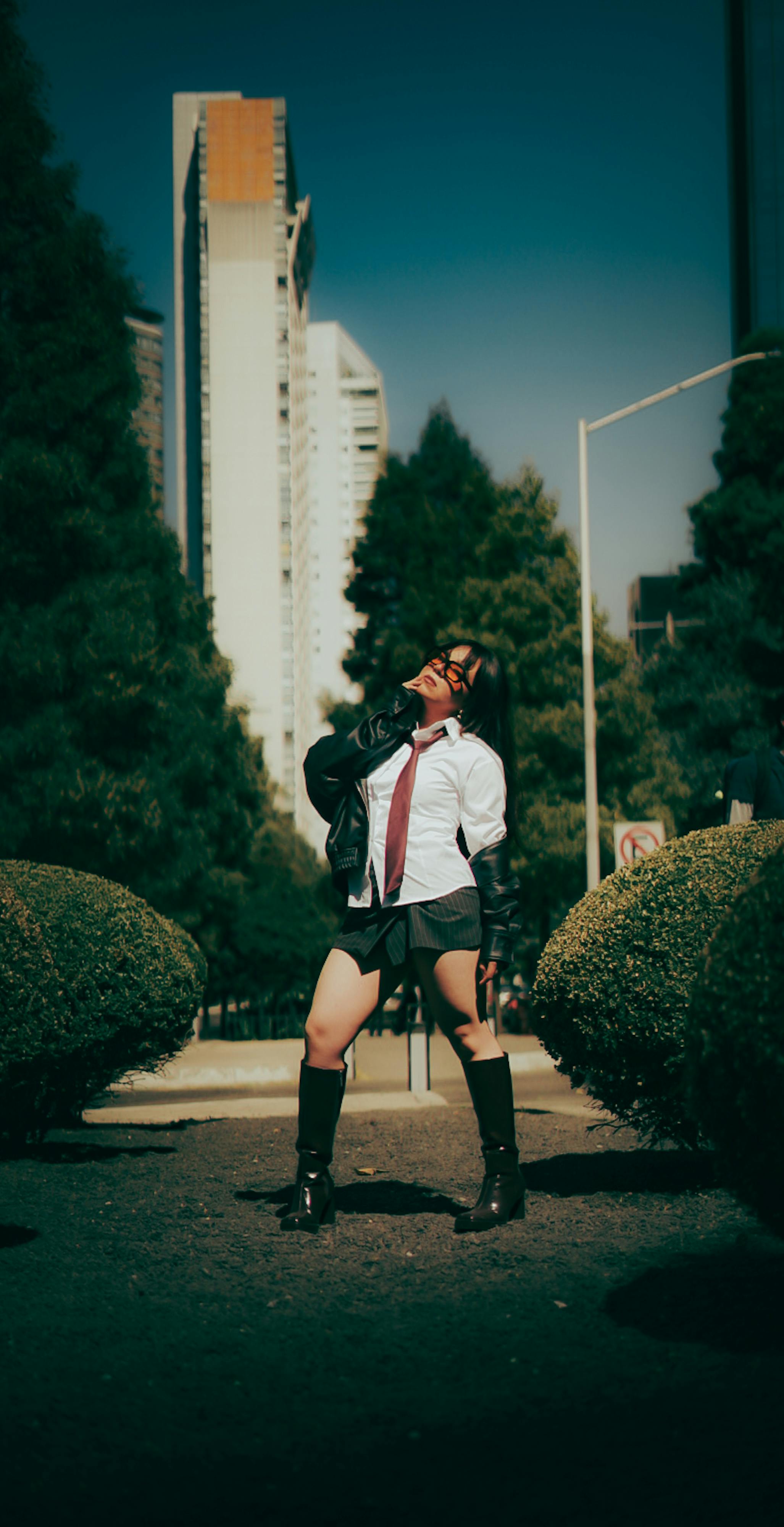 Gratuit Model elegant care pozează în mediul urban, pe fundalul unui zgârie-nori și al unei vegetații luxuriante. Fotografie de stoc