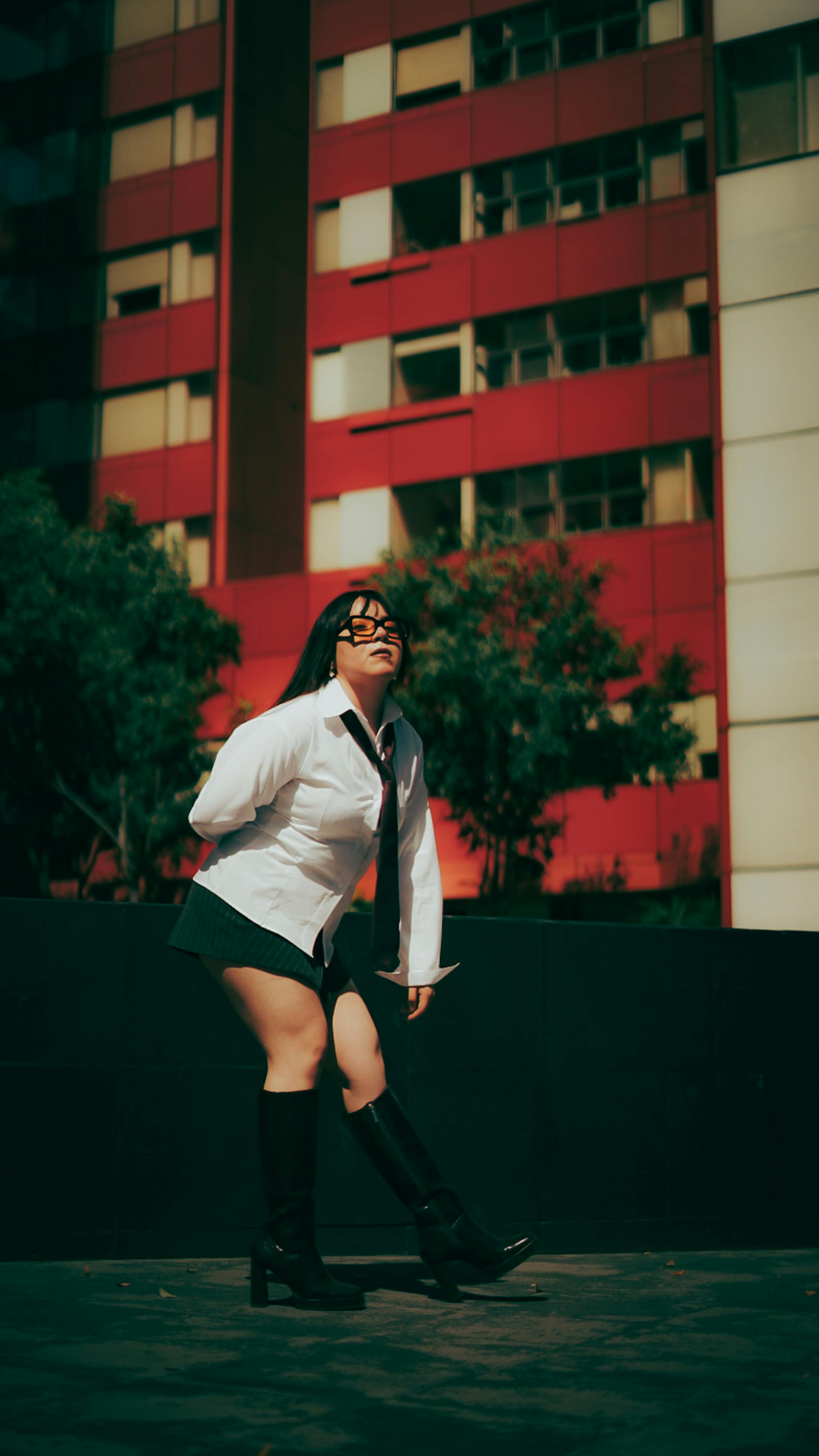 Free Young woman in school uniform poses confidently against a modern urban backdrop. Stock Photo