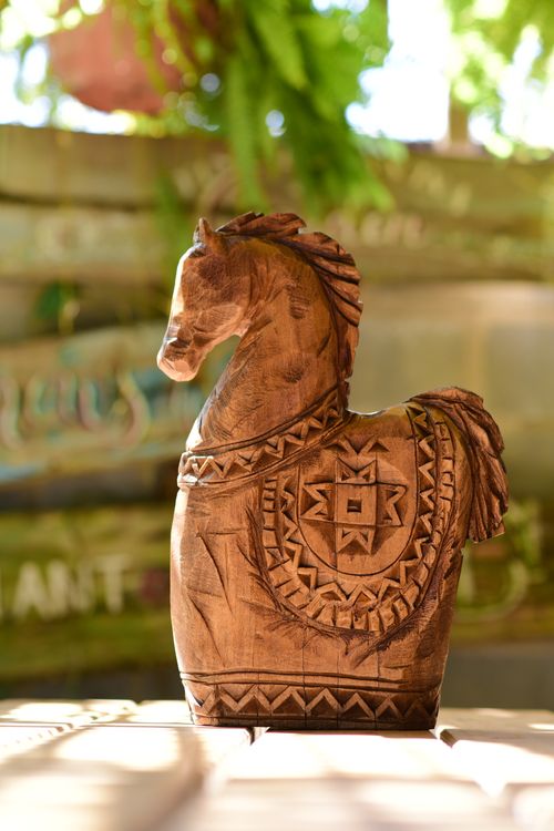 Free A beautifully carved wooden horse sculpture displayed outdoors in natural light. Stock Photo