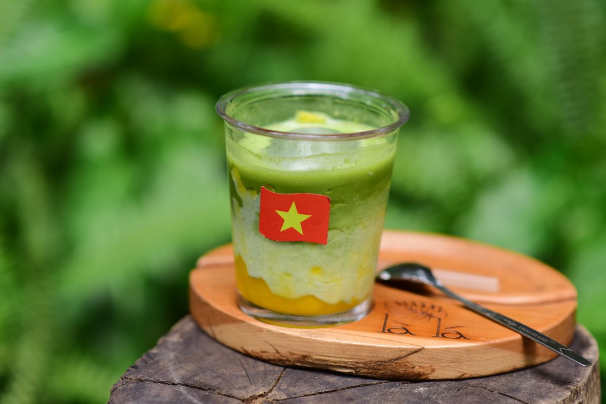 A Vietnamese dessert served in a clear cup with a small national flag