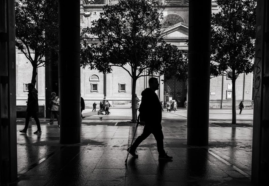 Fotografía en blanco y negro de siluetas caminando por una zona urbana, resaltando la arquitectura.
