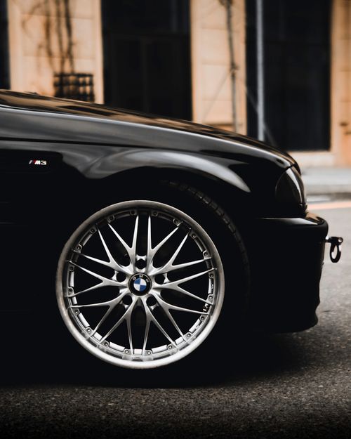Free Close-up of a luxury sports car wheel with shiny chrome alloy rim in an urban setting. Stock Photo