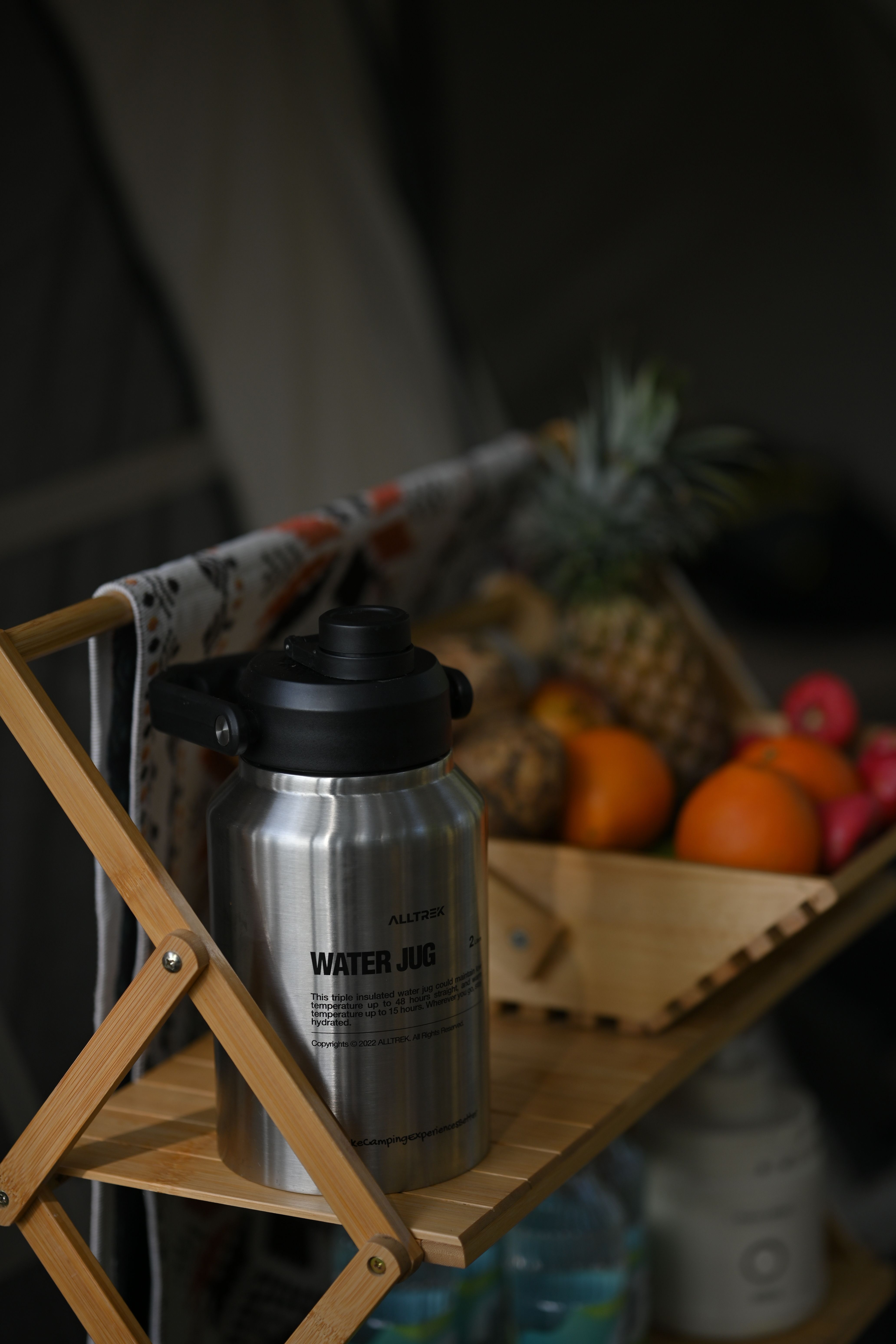 Organized camping gear layout with labeled bins, stove, water jugs, and tent stakes on a picnic table