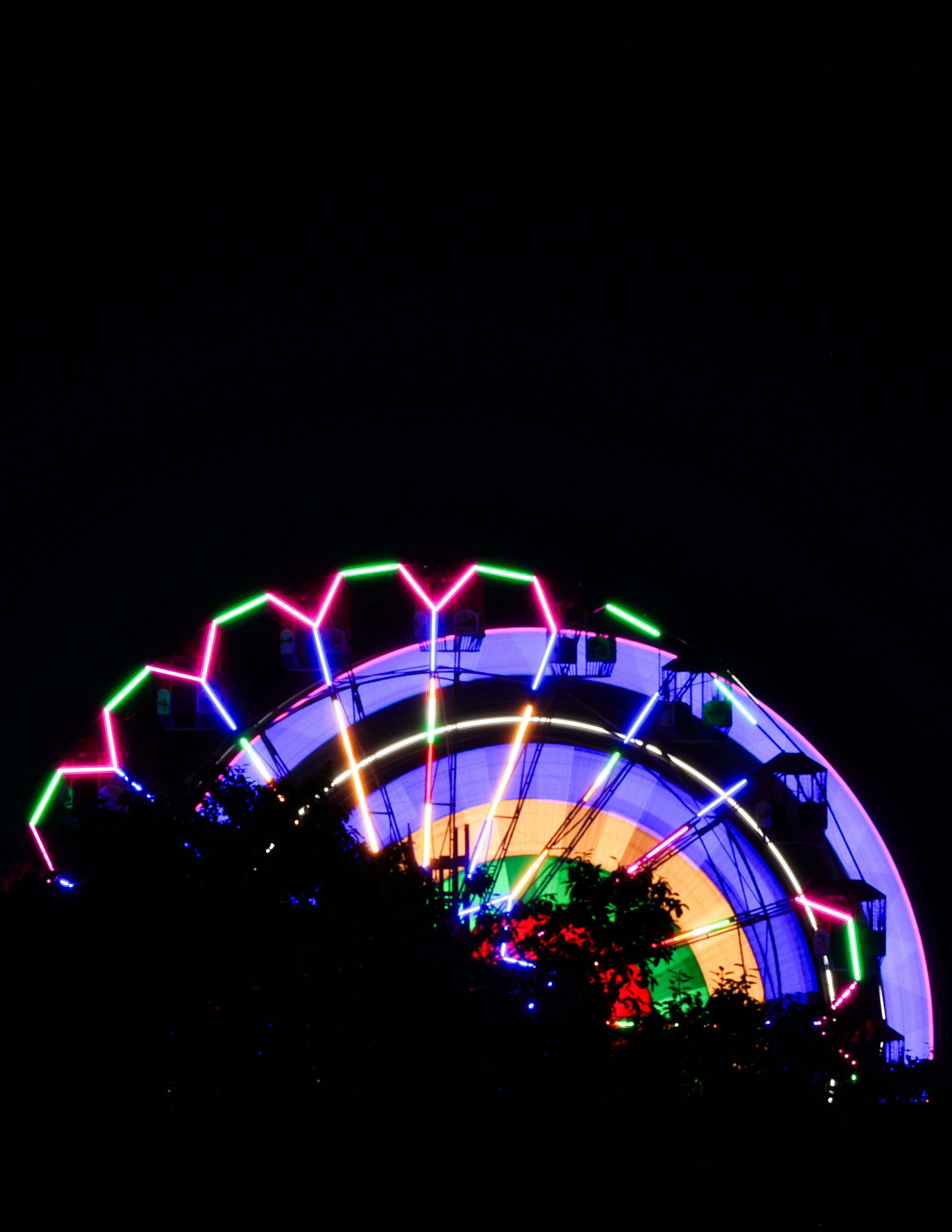 Gratis In India, una ruota panoramica illuminata a giorno risplende di luci al neon colorate contro il cielo notturno. Foto a disposizione