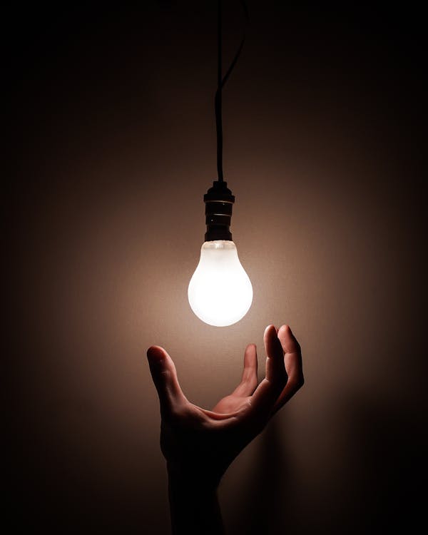 Person reaching White Light Bulb