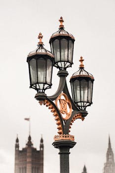 Close-up of a vintage street lantern with iconic London architecture in the background.