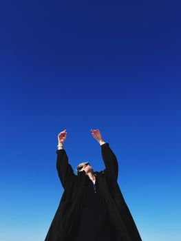 Person celebrating under a vibrant blue sky, conveying freedom and happiness.