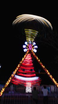 Vibrant night shot of a spinning carnival ride adorned with colorful lights.