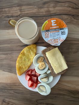 High-protein breakfast featuring eggs, cheese bread, tomatoes, and yogurt.