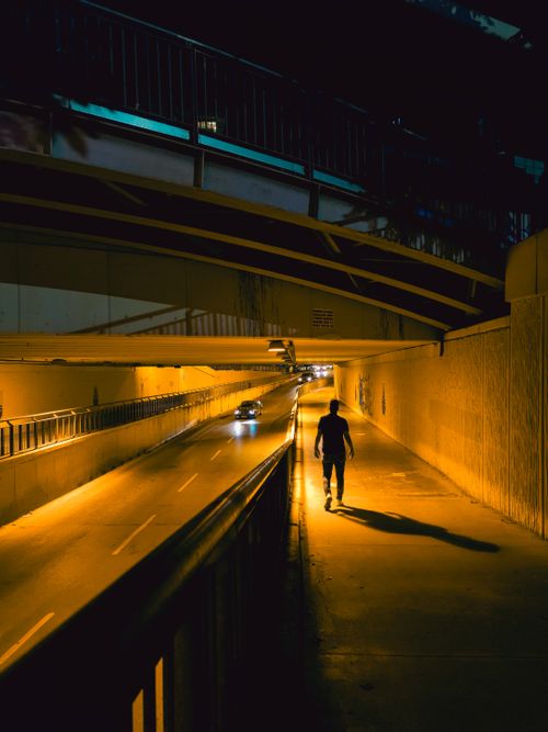 Free Silhouette of a person walking in a dimly lit urban underpass at night. Stock Photo