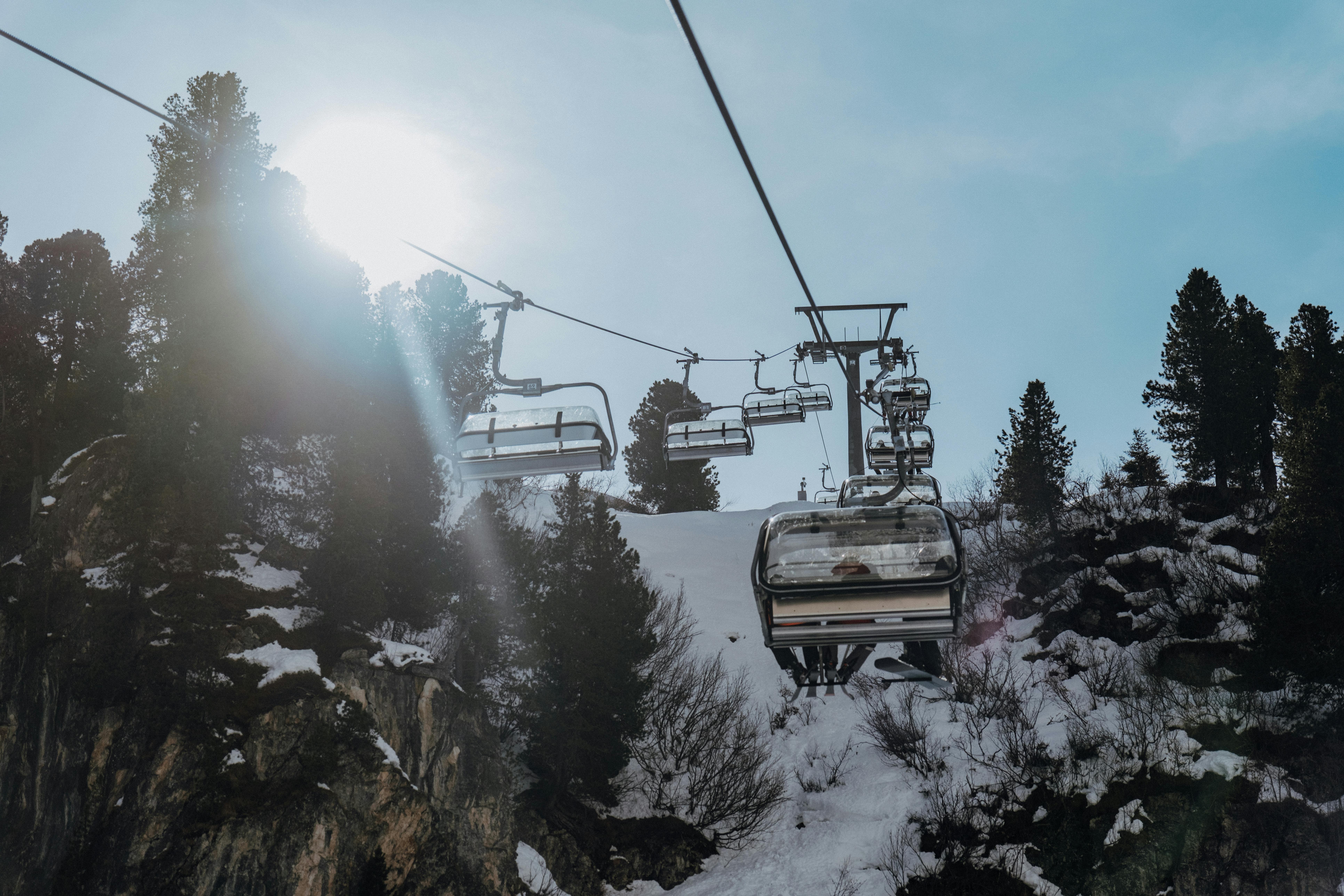 A ski lift ascending a snowy mountain slope under a sunny sky in the Alps.
