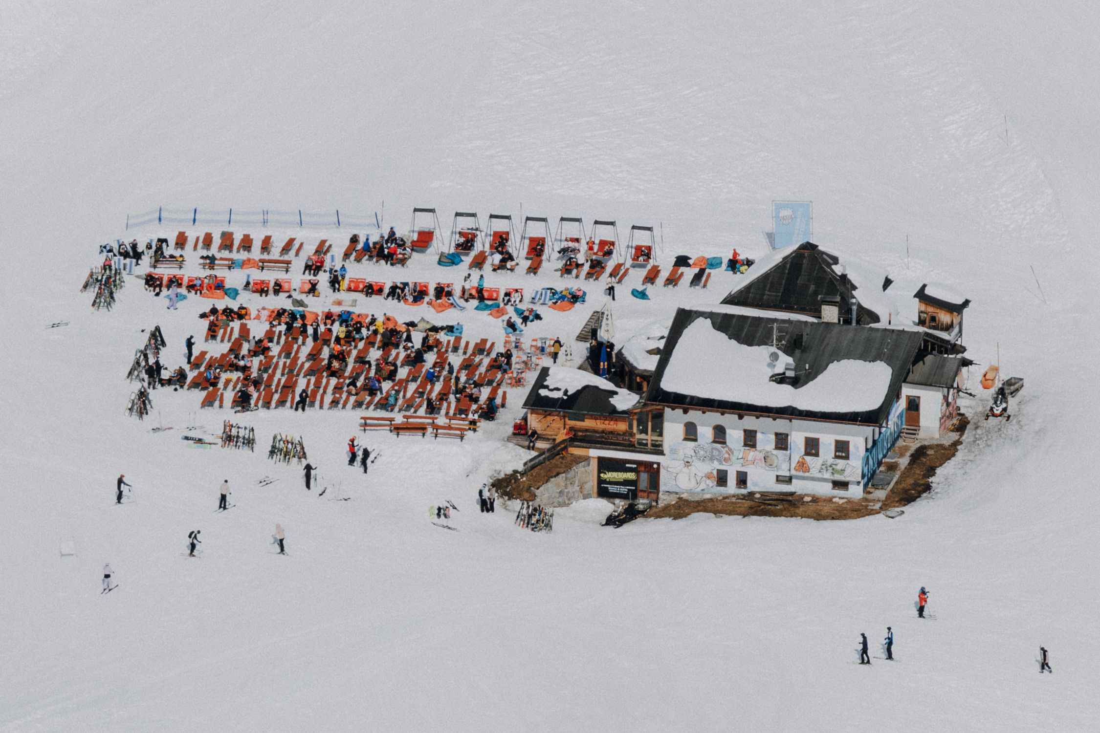 Aerial shot of a ski resort in Mayerhofen, Austria, bustling with skiers and snow-covered chalet.