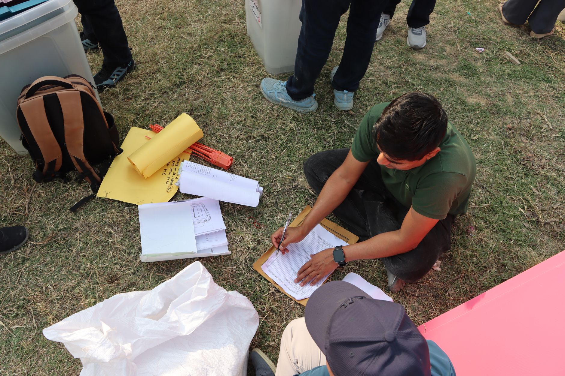 Man sorting electoral papers outdoors in Nepal for upcoming election.
