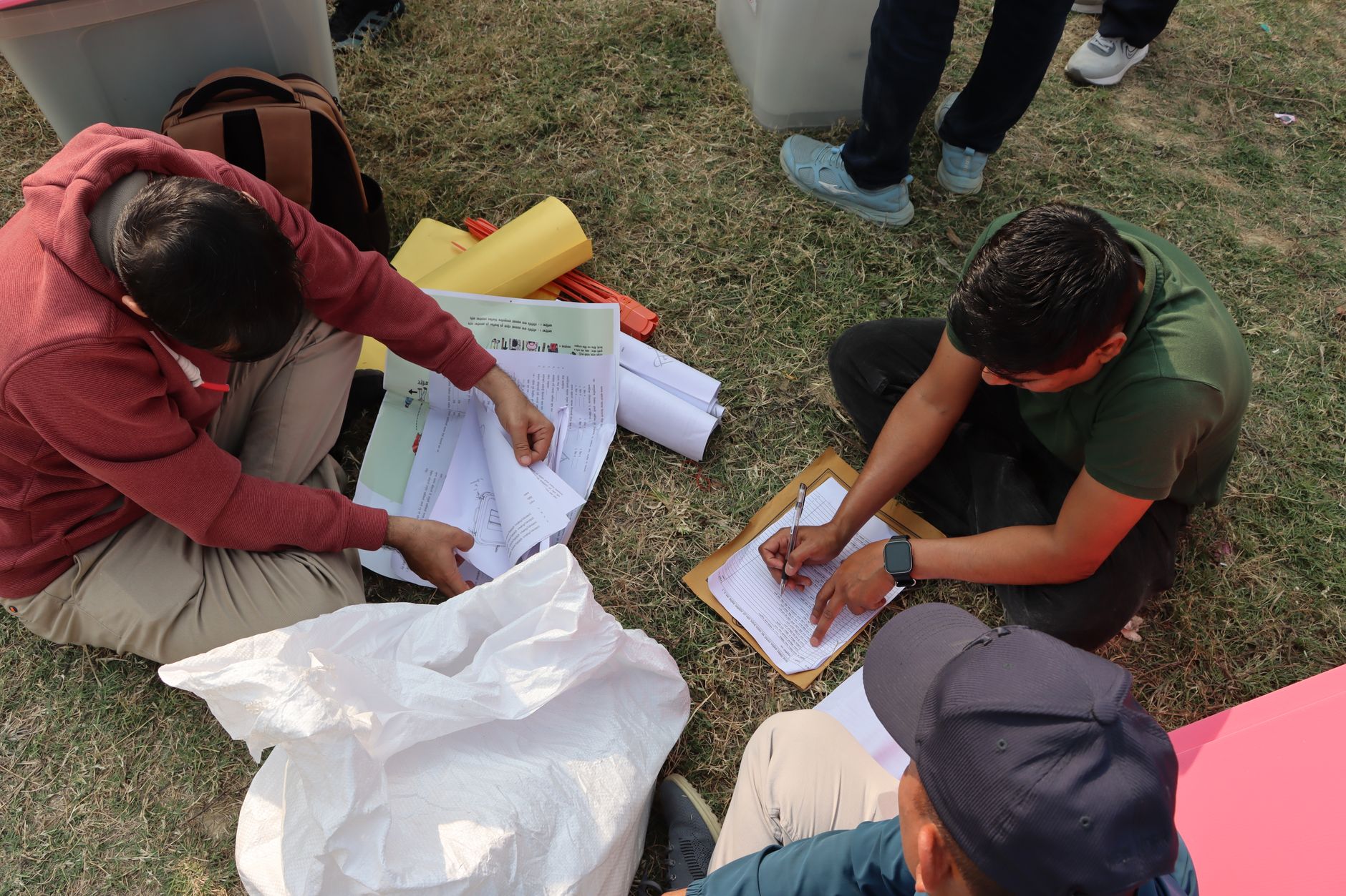 Election officials organizing ballots in an outdoor setting in Nepal, highlighting the electoral process.