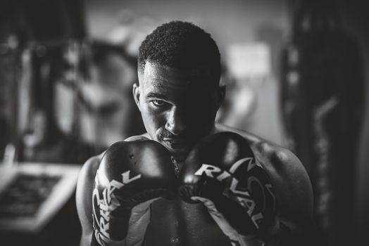 Dramatic black and white portrait of a focused boxer in a gym setting, highlighting strength and determination.