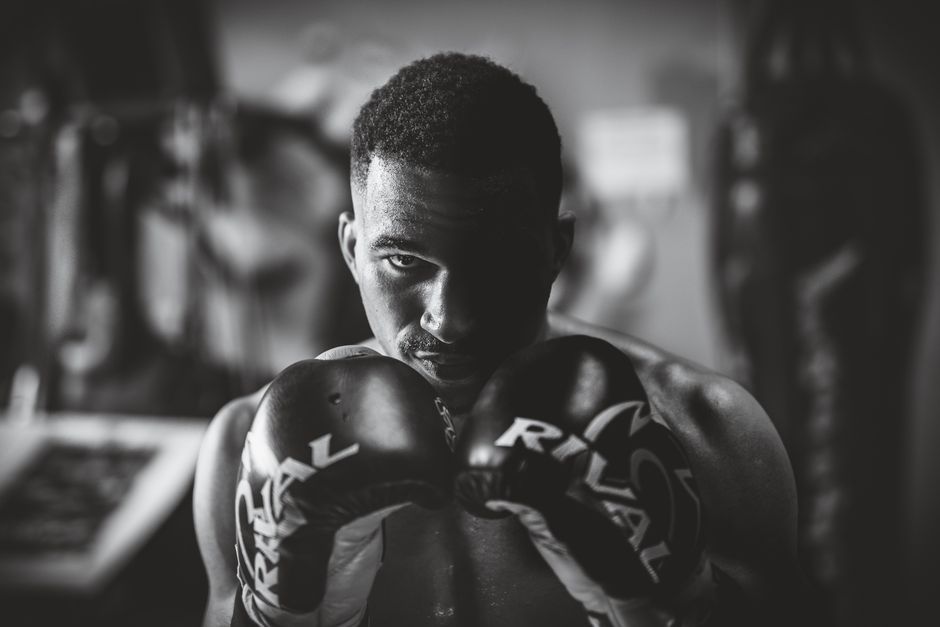 Dramatic black and white portrait of a focused boxer in a gym setting, highlighting strength and determination.