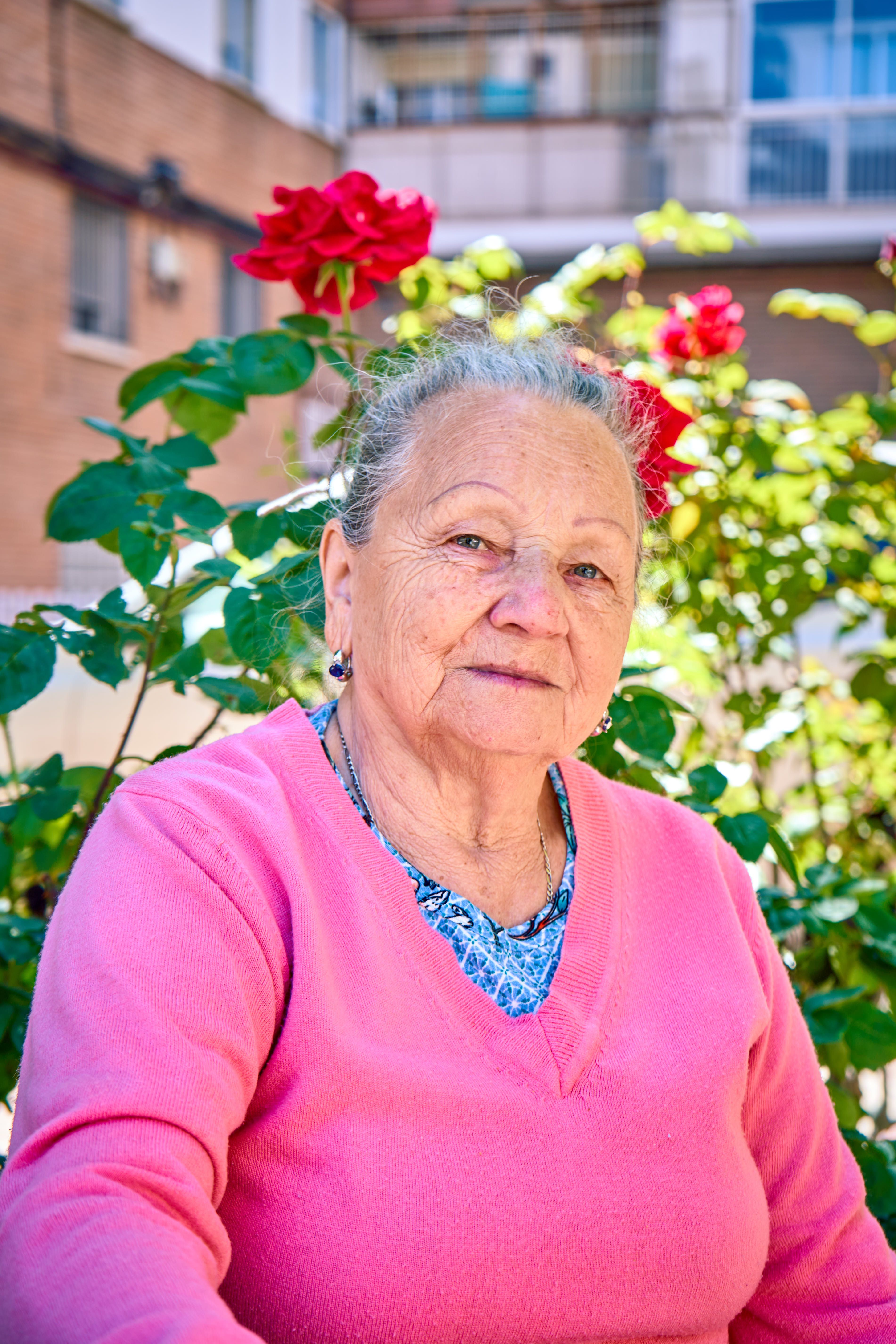Portrait of a senior woman in a vibrant garden on a sunny day.