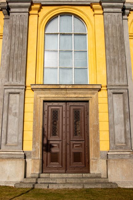 Elegant yellow and gray facade of a historic building with a wooden door in Jönköping, Sweden.