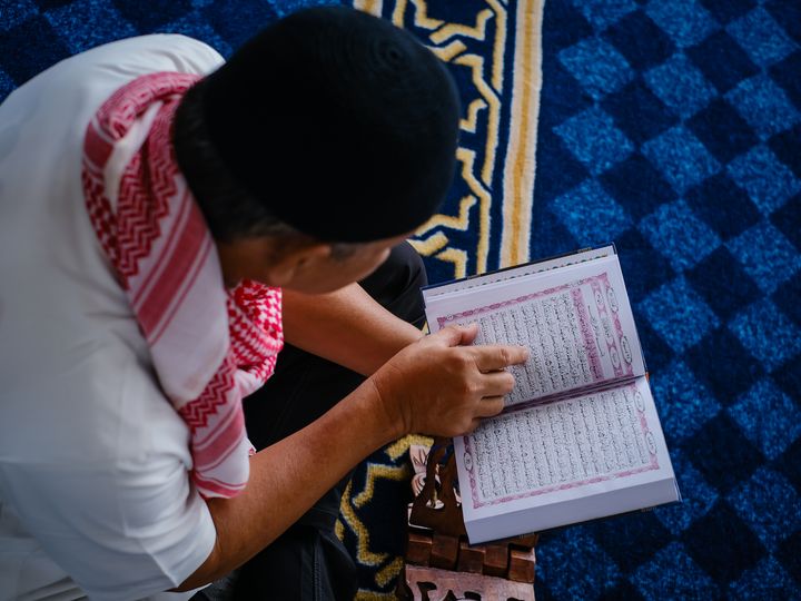 Muslim man reading the Quran on a rehal