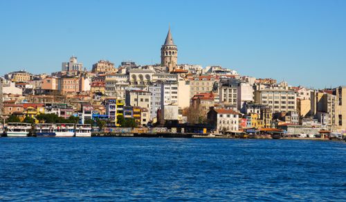 Free A vibrant daytime view of Istanbul's iconic Galata Tower surrounded by historic buildings and waterfront. Stock Photo