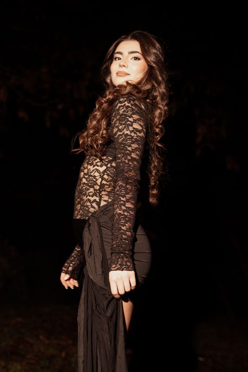 Free Portrait of a woman in lace dress posing stylishly at night, exuding elegance and grace. Stock Photo