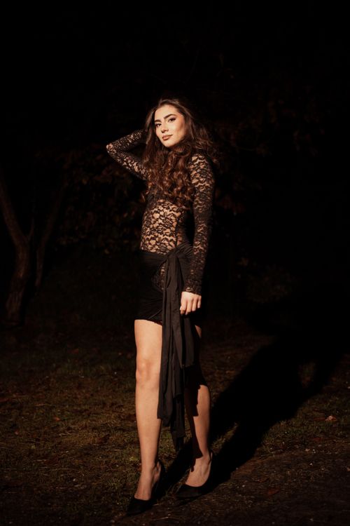 Free A stylish woman poses in a lace dress under night lighting outdoors, exuding elegance and mystery. Stock Photo