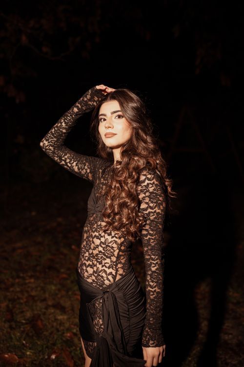 Free Stunning woman in black lace dress posing confidently in a nighttime outdoor setting. Stock Photo