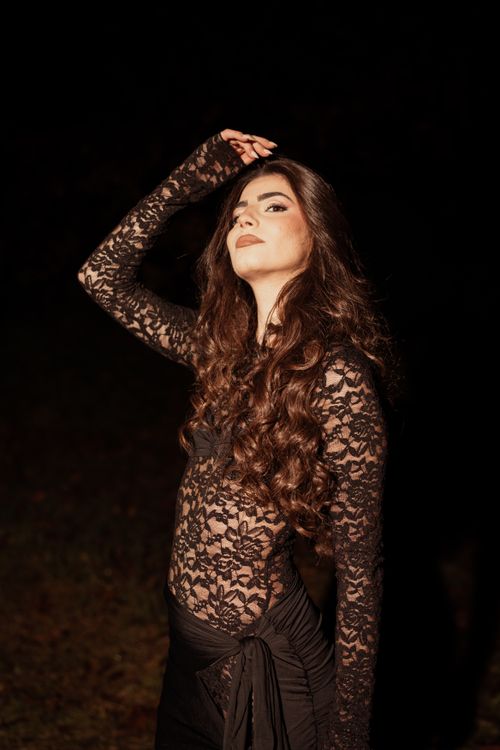 Free Portrait of a stylish woman in a lace outfit posing at night, showcasing elegance and fashion. Stock Photo