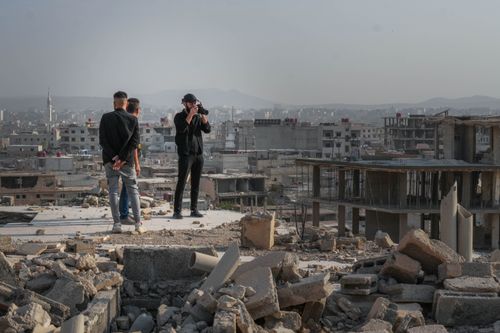 Free Photographers stand among ruins in Damascus, Syria, capturing urban decay. Stock Photo
