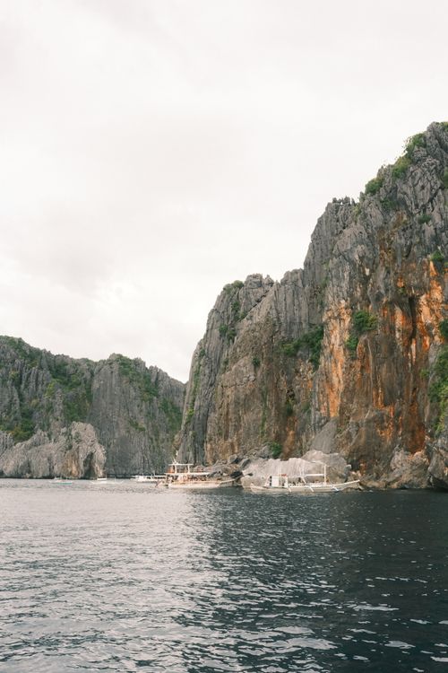 Free Explore the stunning limestone cliffs of El Nido, Palawan with traditional boats docked by the serene ocean. Stock Photo