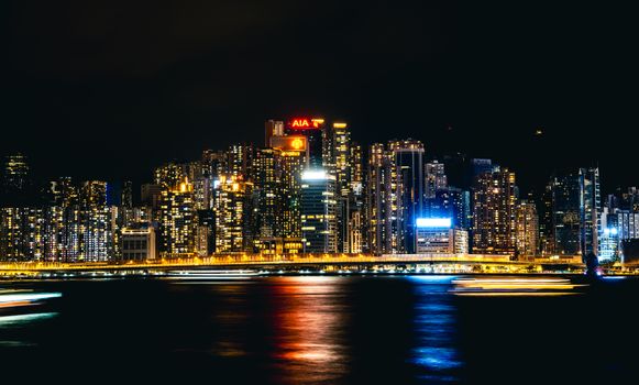 Stunning nighttime view of Hong Kong skyline with illuminated skyscrapers and reflections.