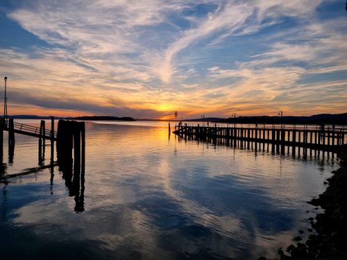 Free Stunning sunset at Lake Trasimeno with pier reflection and vibrant sky. Stock Photo