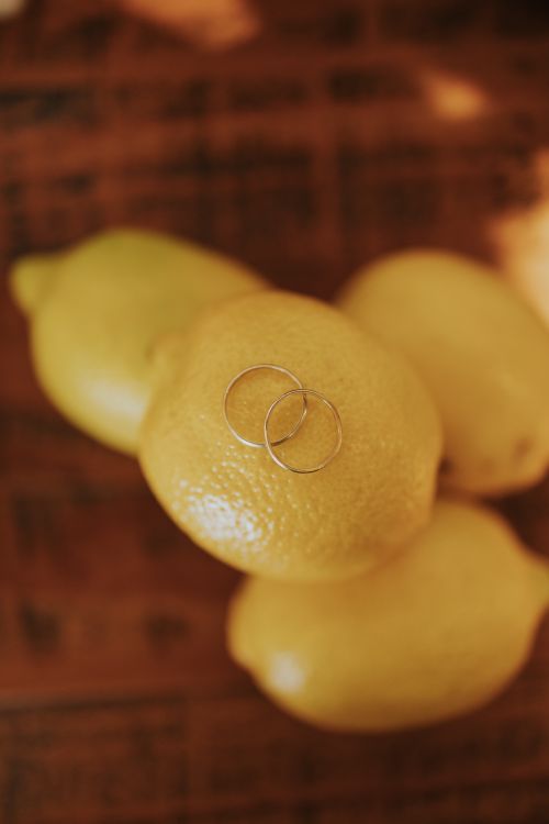 Free Minimalist photo of wedding rings atop bright yellow lemons on a wooden surface. Stock Photo