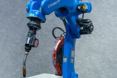 Industrial robotic welding station featuring a blue robot arm welding a metal object.