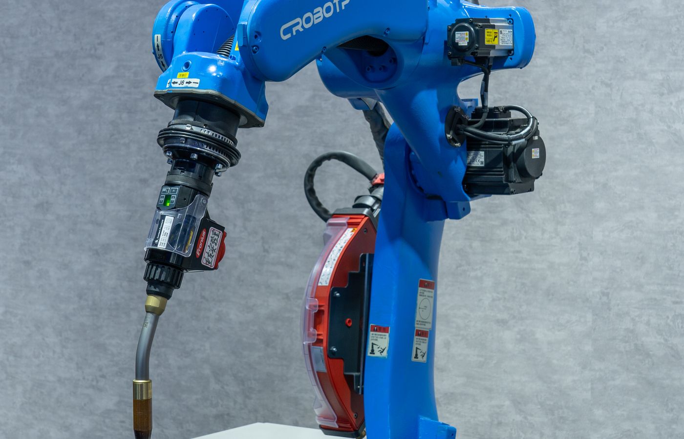 Blue industrial robot arm operating at an automated metal-welding station