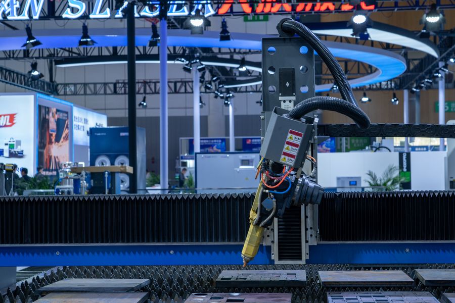 A CNC laser machine operating in a high-tech industrial exhibition setup with vibrant lighting.