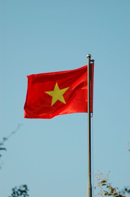 Free The Vietnamese national flag waving proudly against a clear blue sky. Stock Photo