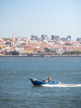 A picturesque view of Lisbon with a small boat on the Tejo River capturing the city's charm and vibrancy.
