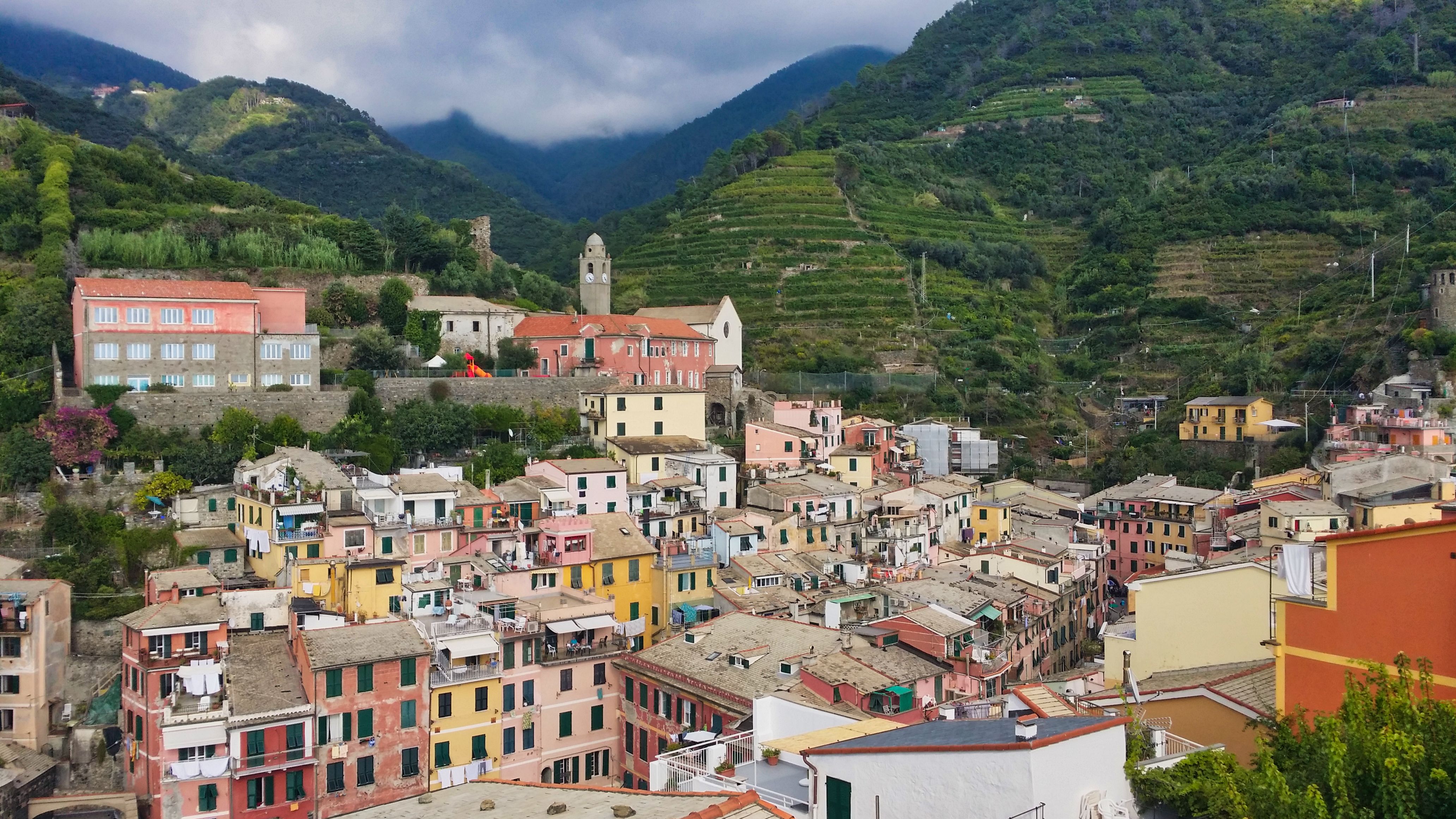 Aerial view of colorful Vernazza village surrounded by lush green hills in Liguria, Italy.